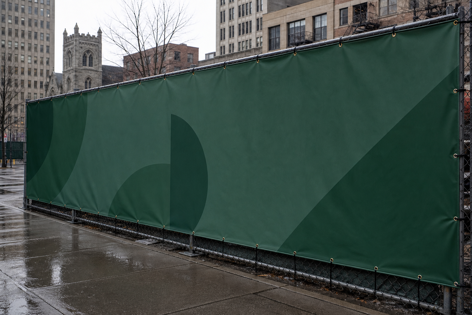 A large printed vinyl banner tensioned across a construction fence on a city street